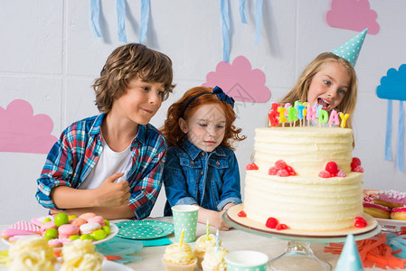可爱的快乐的孩子在生日餐桌背景图片