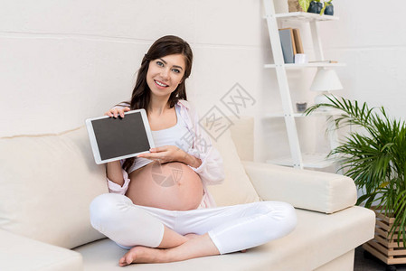 孕妇坐在沙发上用数字平板电图片