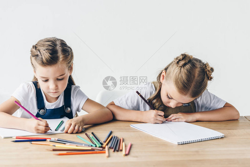 可爱的小女学生用彩色铅笔在专辑上画与白图片