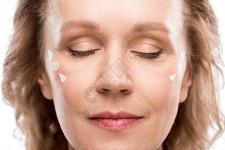 成年妇女脸上有化妆奶油和眼睛闭图片