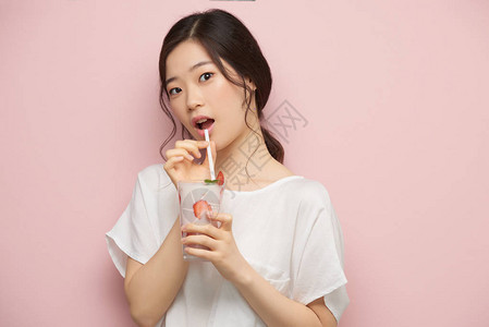 美丽的韩国女人喝草莓图片