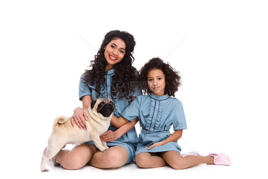 母亲和女儿坐在地板上与小巴格图片