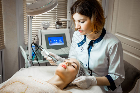 医生美容师在美容院里为一位美丽的年轻女子的面部皮肤进行了面部注射程序图片