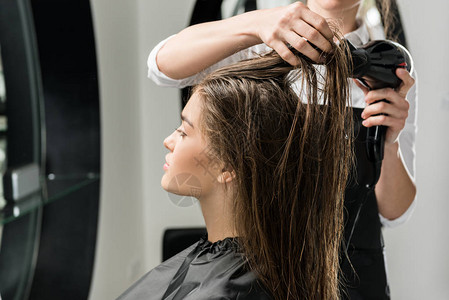 美发师在美容院吹干年轻女子的头发图片
