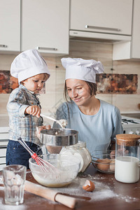 妈和可爱的小孩在厨师帽准备钱在厨图片