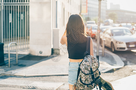 背着包和溜冰鞋在城市背光中行走的年轻美丽亚洲女膝盖后视图图片