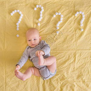 在床上用棉球做成的问号围着婴儿躺着时图片