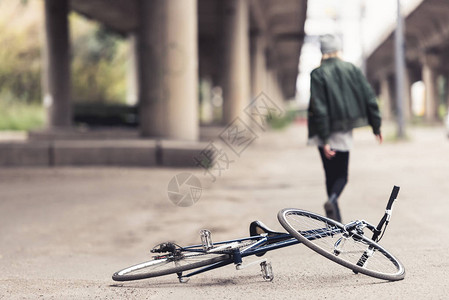 妇女离开旧自行车后躺在沥青上图片