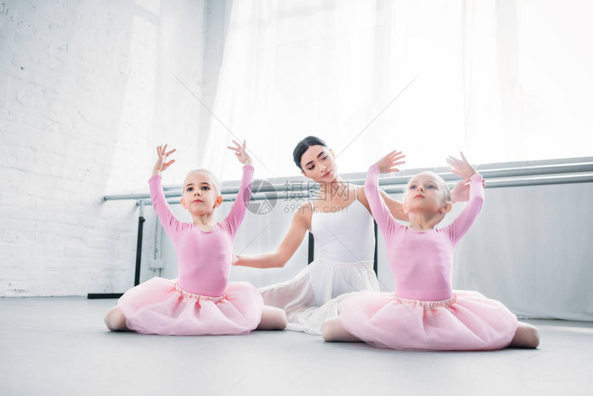 年轻芭蕾老师看着穿礼裙子的可爱小孩在图片