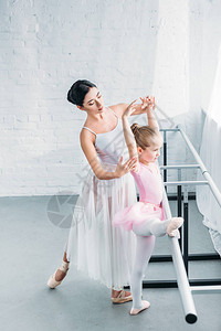 年轻芭蕾教师在芭蕾舞演播室与可爱的图片