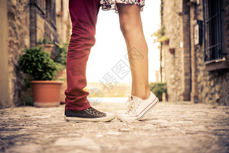 内奇拉达一对夫妇在户外亲吻日落时浪漫约会的情人女孩们站在脚尖上背景