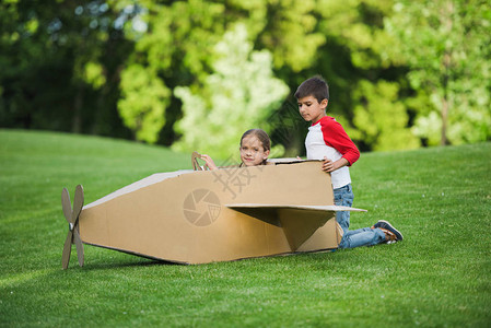 可爱的小孩在绿色公园玩纸板飞机图片