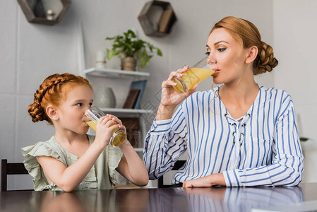 母亲和女儿早上喝橙汁互相看着对方图片