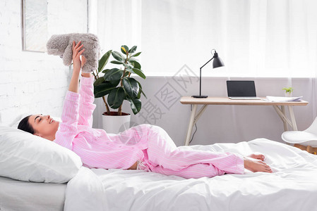 穿着粉色睡衣的女人的一面家里床图片