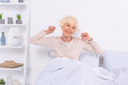 喜悦的年长妇女在家床图片
