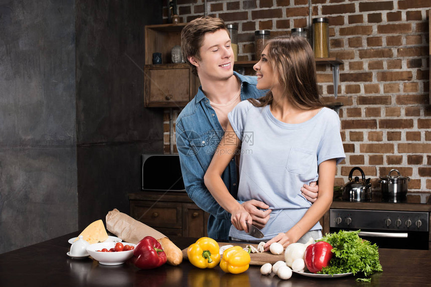 男人拥抱女友而她在家里厨房做饭时却在图片