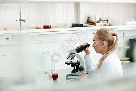 利用显微镜在医学实验室研究血液的美貌金发女子图片
