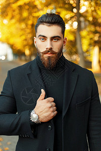 一个长胡子和胡子的时装男子的秋天肖像穿着黑色时髦大衣和阳图片