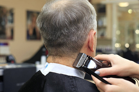 从理发师那里理发的男人专业理发店老人的侧面肖像老人剃光图片