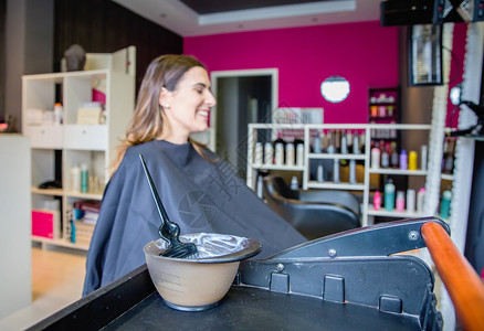 与背景中的女客户一起为改变发色而准备的梳子和碗图片