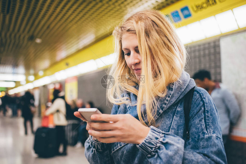 年轻的金发女子在地下使用智能手机图片