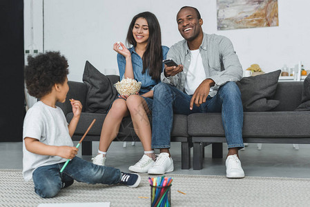 African美长观看电视和儿子在家里图片