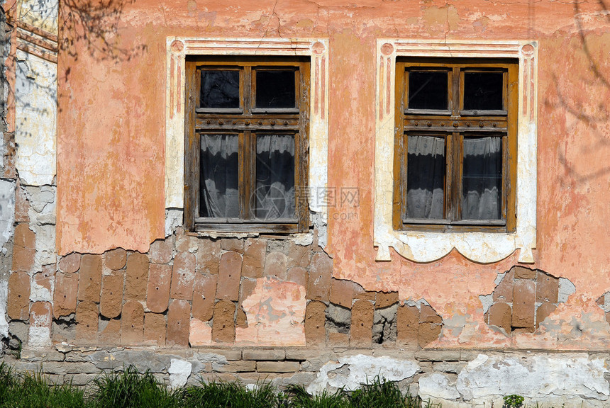 房子墙壁的特写镜头有两个旧窗户的图片