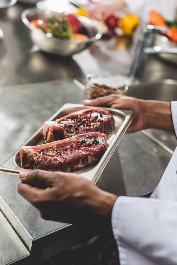 非洲人厨师在餐厅用生肉端着餐盘的图片