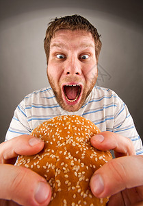 吃多汁汉堡的富有表现力的人肖像图片