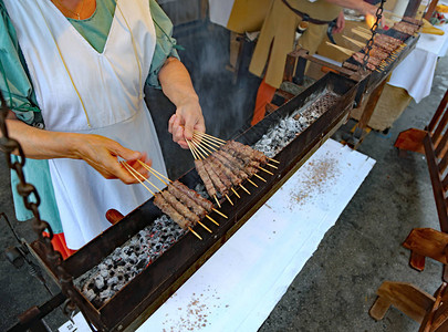 女人在街上做饭很多吃鸡肉的牛排用烤背景图片