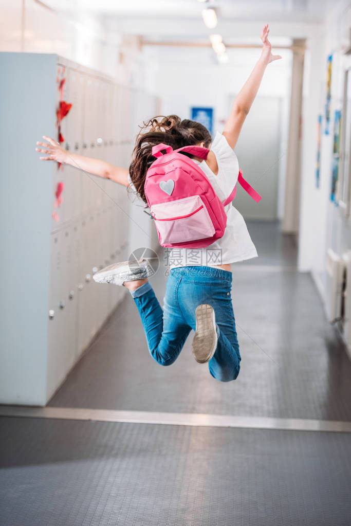 女孩举手在学校走廊跳跃的背影图片