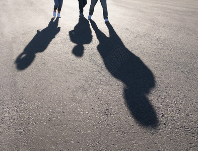 三个人在柏油路上行走的影子背景图片