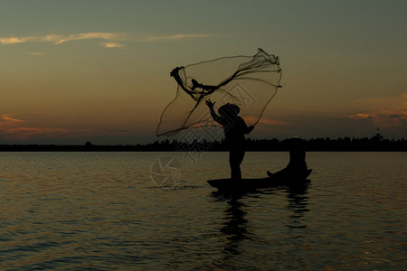 剪影渔夫在小船渔网上图片