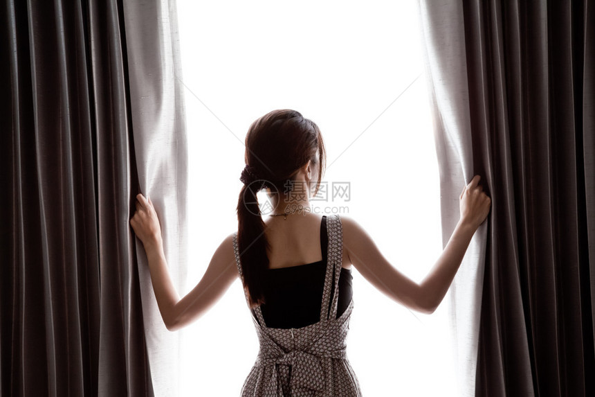 年轻女子拉开窗帘图片