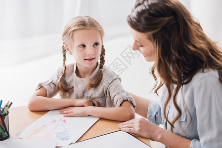 快乐的心理学家与剪贴板坐在小孩身边图片