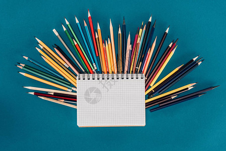 蓝色背景中孤立的空白笔记本彩色铅笔图片