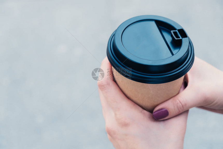 咖啡用棕色纸板杯和黑色帽子在沥青背图片
