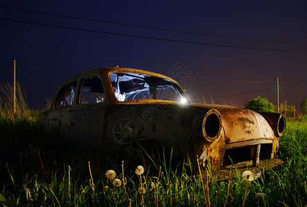 夜间废弃的生锈汽车残骸背景图片