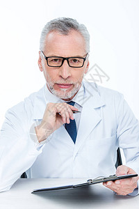 戴眼镜的男医生在望着照相机并用白色图片