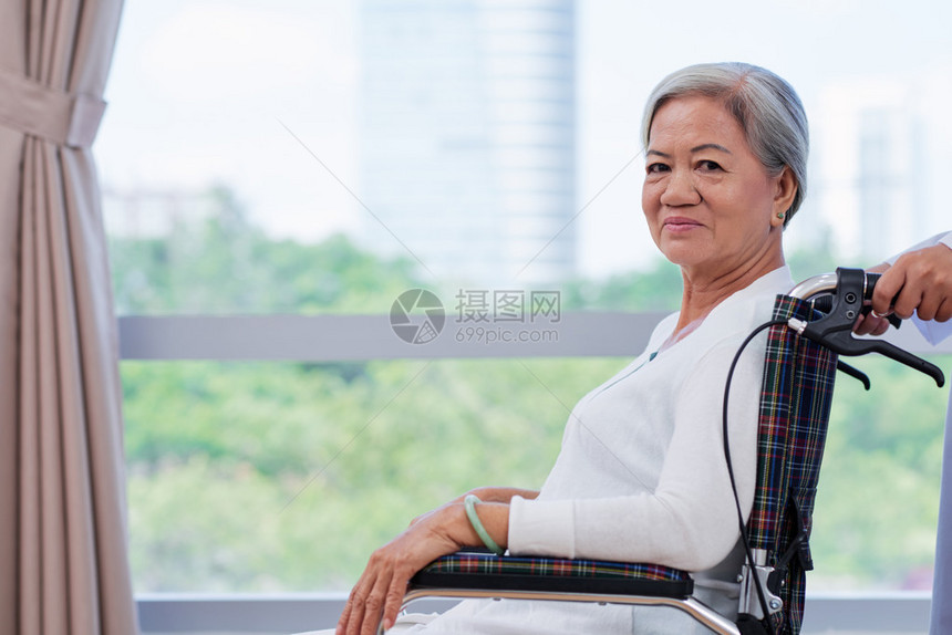 坐在轮椅上的越南妇女笑着微笑的高级肺部X光照越图片