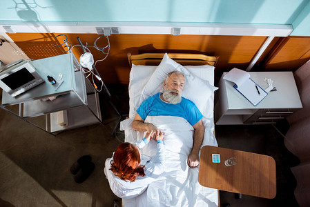 坐在医院床上的高级男患者手掌女医生的图片