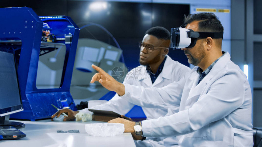 身穿医服的多种族男子在VR眼镜中探索3D飞毛腿模型并讨论运动稳图片