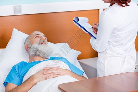女医生与躺在医院床上的高级病人交谈图片