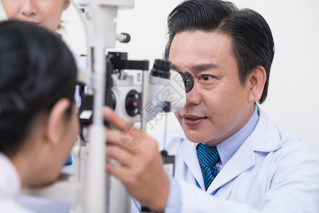 中年越南医生检查病人眼睛的图片