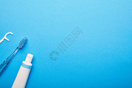 蓝色背景上排列的牙线牙刷和牙膏的顶视图片