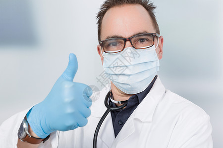 戴着医用口罩和蓝色医用手套的医生竖起大拇指图片