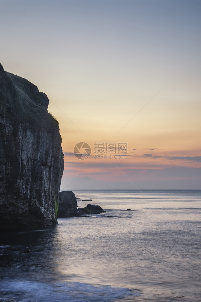 日出时海浪撞上岩石使沿海景观受到长图片