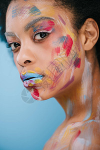 美丽的年轻美女脸面上涂着彩色的画笔图片