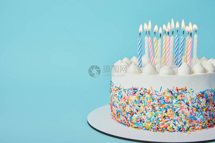 蓝色背景上点着蜡烛的美味生日蛋糕图片