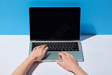 使用白桌和蓝背景空白屏幕的笔记本电脑观看被作背景图片